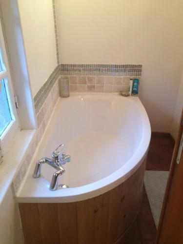 La salle de bains est pourvue d'une baignoire blanche et d'un lavabo. dans l'établissement Maison Bleu, à Puilaurens