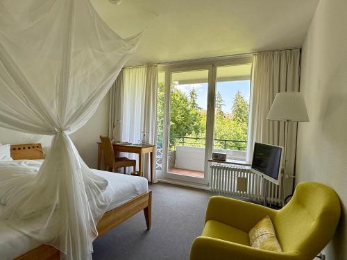 a bedroom with a bed and a balcony with a television at FX Mayr Zentrum Bodensee in Überlingen