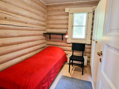 a log cabin bedroom with a red bed and a desk at Villa Äijänhonka 10 - 6 hlö, Himos Honkaranta in Himos