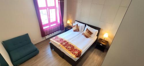 a bedroom with a bed and a blue chair at Sun-House Pension&Restaurant -ParkingFree- in Prague