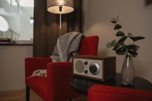 a room with a table with a radio on a red chair at Home Hotel Odin in Gothenburg