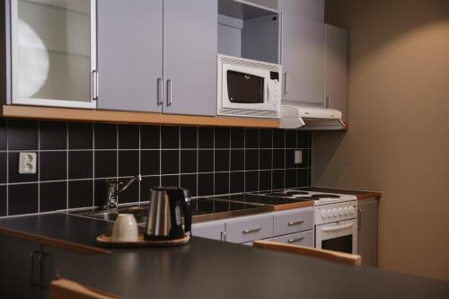a kitchen with white cabinets and a sink and a microwave at Home Hotel Odin in Gothenburg
