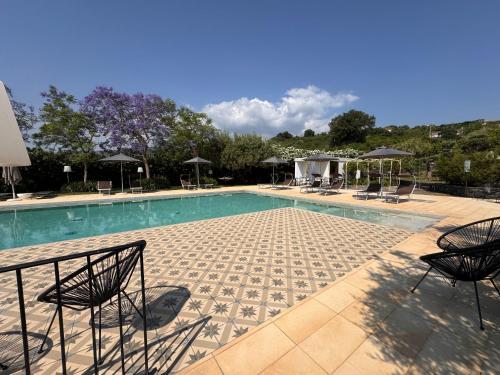 a swimming pool with chairs and umbrellas at Talè Restaurant & Suite in Piedimonte Etneo