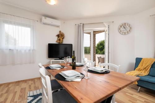 a dining room with a wooden table and a tv at Apartments ADELA in Polje