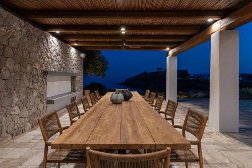 a long wooden table and chairs on a patio at Villa Calma a Beachfront Luxury Retreat in Porto Heli