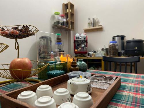 - une table avec un plateau avec des tasses et une pomme dans l'établissement DA Travel Home - Hanoi Hostel, à Hanoï