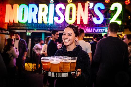 a woman holding a tray of beers in a bar at Full Moon Budapest in Budapest