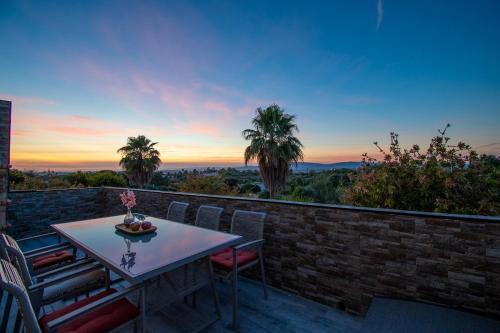 a table and chairs on a balcony with a sunset at Apartment Bela Vista in Estômbar