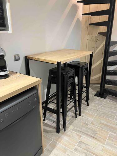 une table en bois avec des tabourets noirs dans une cuisine dans l'établissement La petite maison du gardien, à Avignon