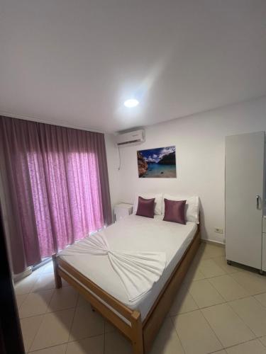 a bedroom with a large bed with pink curtains at Hotel PEJA in Velipojë