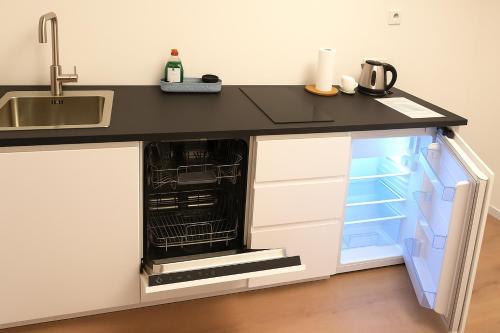 a kitchen with a black counter top and an open dishwasher at Glacier World - Hoffell Guesthouse in Hoffell
