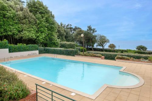 une grande piscine bleue sur un patio carrelé dans l'établissement Appart à 100m de la plage - piscine pour 4, à Pornic