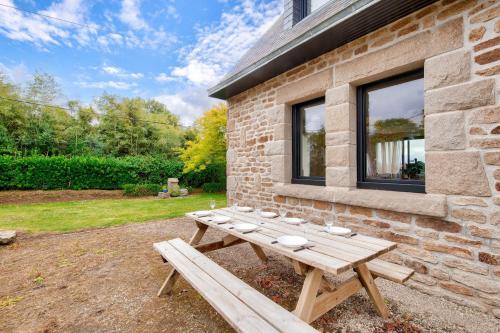 a wooden picnic table in front of a brick building at Vue mer - Maison pour 8 - Grand jardin in Lannilis