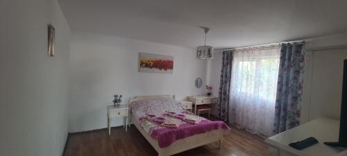 a bedroom with a bed and a table and a window at Casa Geo in Vadu