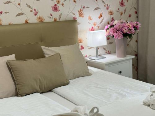 Un dormitorio con una cama con un jarrón de flores en Amfora Panzió, en Gyula