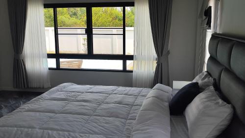 a bed in a bedroom with a large window at Avipoolvilla in Hang Dong