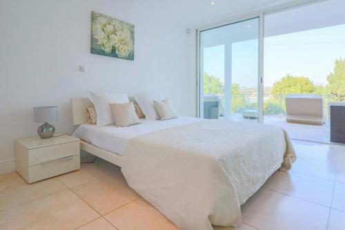 une chambre blanche avec un lit et une grande fenêtre dans l'établissement EDEN ROC Luxurious villa with sea view & huge pool in Cap d'Antibes, à Antibes