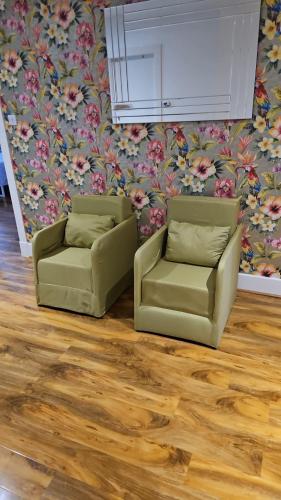 two chairs and a couch in a room with flowers at Perfect Stay Near Glasgow Town in Glasgow