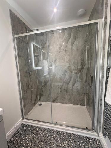 a shower with a glass door in a bathroom at Lakeside Log Cabin in Legbourne