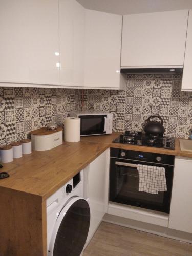 a kitchen with white cabinets and a stove and a dishwasher at Sopocka Przystań - Domek Letniskowy in Ciotusza Stara