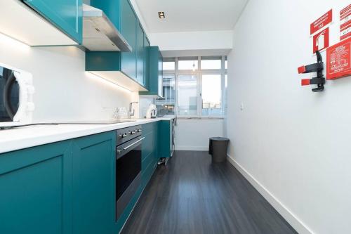 a kitchen with blue cabinets and wooden floors at Lisbon Hideaway near the River in Lisbon