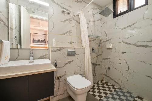 a bathroom with a toilet and a sink at SaffronStays Rio in Nerul