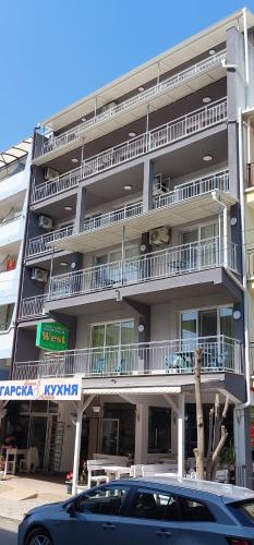 a blue car parked in front of a building at Guest house WEST in Sunny Beach