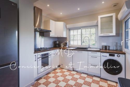 une cuisine avec des armoires blanches et un sol carrelé dans l'établissement Villa Puerta Del Sol - Capbreton Centre, à Capbreton