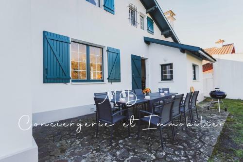 un patio avec une table et des chaises devant une maison dans l'établissement Villa Puerta Del Sol - Capbreton Centre, à Capbreton