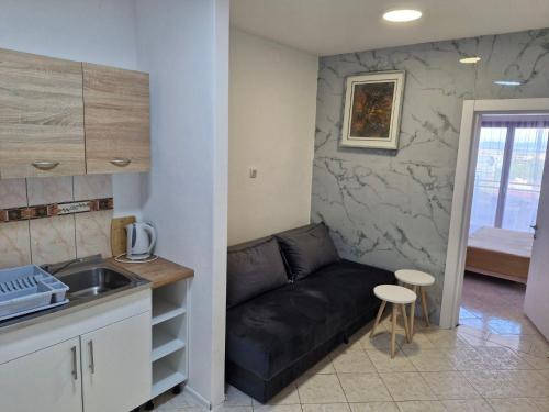 a living room with a black couch and a kitchen at Aparments Plaza in Velika Plaža