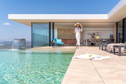 a woman is standing next to a swimming pool at Villas Aloe Vera by Abahana Luxe in Benitachell