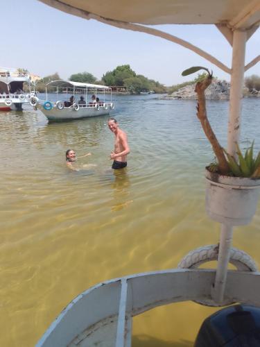a man and a woman in the water with a boat at Nubian Life Nile View in Aswan