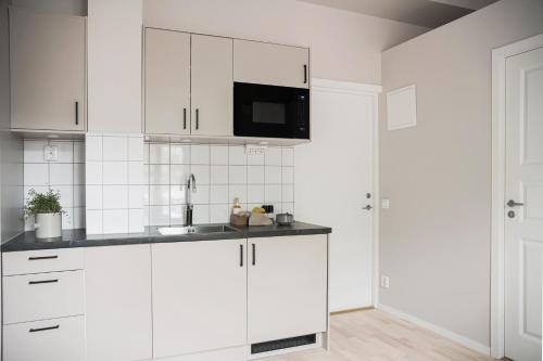a white kitchen with a sink and a microwave at Mörrum River Residences in Mörrum