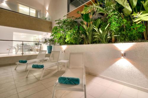 a restaurant with white chairs and plants on the wall at Olymp Luxury House - Ultra Luxury Beachfront Villa with Rooftop Lounge in Paphos