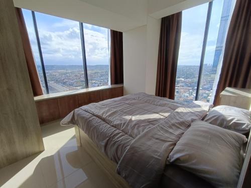 a bed in a room with large windows at 2BR Pollux Habibie Meisterstadt Tower 1 Batam City in Batam Center
