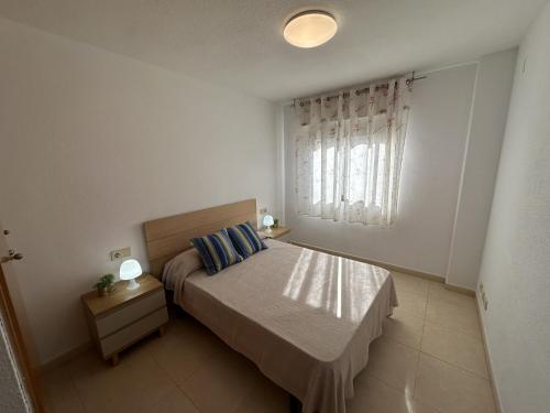 a white bedroom with a bed and a window at Sirocco Apartamento in Oropesa del Mar