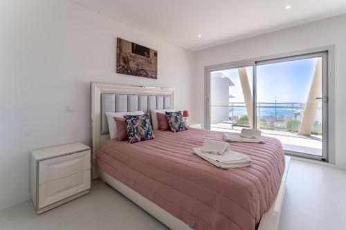 Un dormitorio con una cama grande con una ventana grande. en Apartamento T2 Azure Coast, en Nazaré