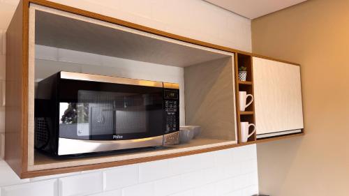 a microwave in a cabinet in a kitchen at Villa Cristalle - Campos do Jordão in Campos do Jordão
