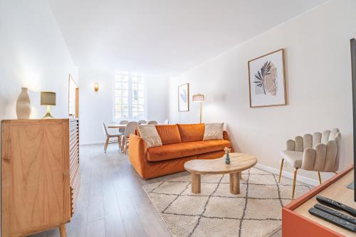 a living room with an orange couch and a table at Appartement 2 chambres en Hyper Centre avec balcon in Bordeaux