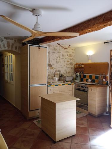 Il comprend une cuisine avec des placards en bois et un ventilateur de plafond. dans l'établissement Maison dans hameau provençal, au Luc