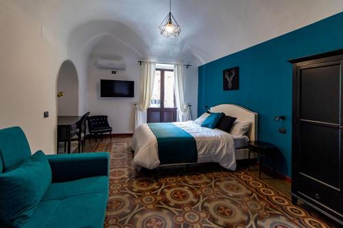 Un dormitorio con paredes azules y una cama y un sofá. en Siculis Domus, en Catania