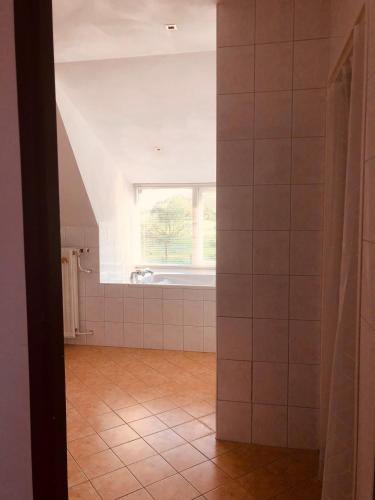 a bathroom with a window and white tiled walls at Slapen bij de Brug in Zuidveld