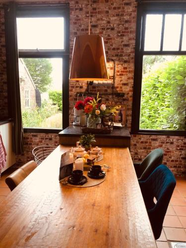 a large wooden table in a room with windows at Slapen bij de Brug in Zuidveld