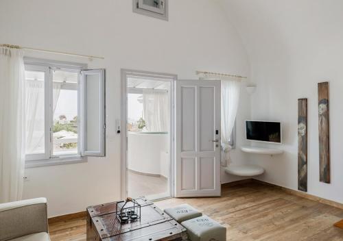 a white living room with a couch and a tv at Orabel Suites Santorini (Adults Only) in Perivolos
