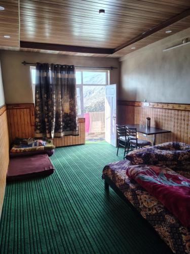 a room with two beds and a table and a window at Nako valley home stay in Nako