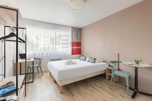 une chambre d'hôtel avec un lit, une table et des chaises dans l'établissement Appart'City Classic La Rochelle Centre, à La Rochelle