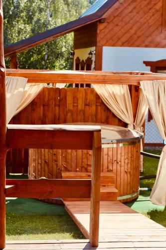 a wooden bench sitting on a deck with a hot tub at Domki Eden Kaszuby balia sauna alpaki mini zoo in Gołubie
