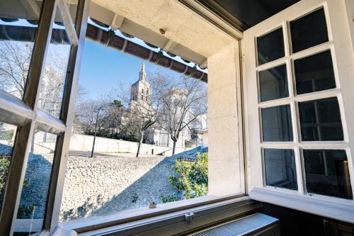 une fenêtre ouverte avec vue sur une église dans l'établissement La Lucarne du Palais - Clim et Wifi - Vue sur le Palais des Papes à 20m, à Avignon