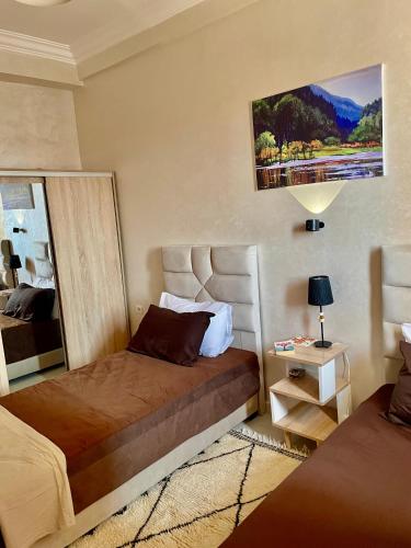 a bedroom with two beds and a painting on the wall at Appartement cosy 2 min aéroport Marrakech 2 chambres bien équipé in Marrakech