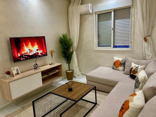 a living room with a couch and a tv at Appartement cosy 2 min aéroport Marrakech 2 chambres bien équipé in Marrakech